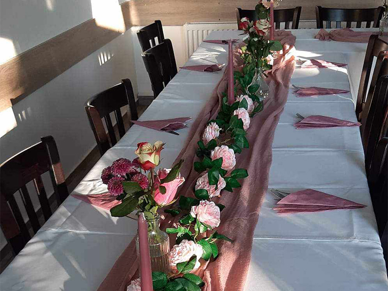 Ein Tisch mit rosé farbenen Tischschmuck, Kerzen, Servietten und rosa Blumen